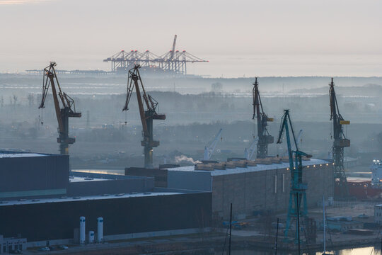 Aerial view of the industrial port cranes and DCT Gdansk container terminal under a misty morning sky in Gdansk, Wojewodztwo pomorskie, Poland.