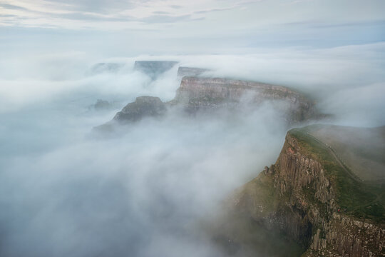 Aerial view of Giants Causeway shrouded in thick morning mist and fog over the rugged basalt cliffs Bushmills, Northern Ireland, United Kingdom.