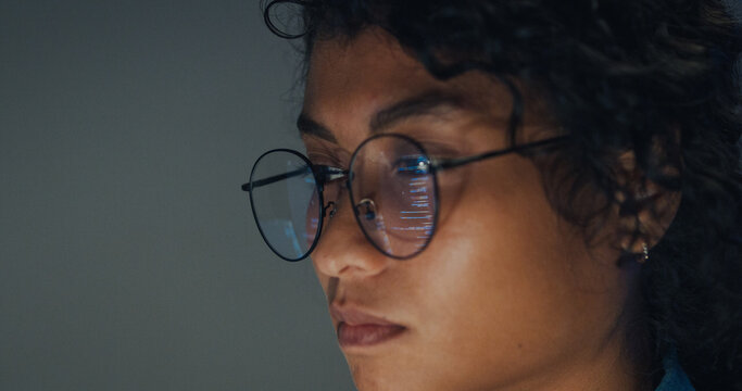 Close-up Black female programmer with code reflection in glasses working late in home office at night. Cybersecurity, AI algorithm, Network security, software developer, serious face, burnout concept.