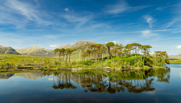 Twelve Pines Island reflected in Derryclare Lough, Connemara, County Galway. Scenic lake and mountain landscape in the heart of the Twelve Bens region, Ireland