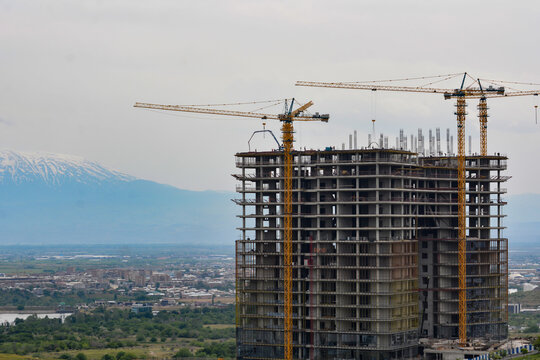 Construction of a new residential complex with cranes in the city. Construction of a multi-storey building with cranes in the background. Rise building in the city