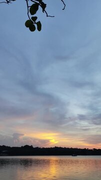 Video footage of a lake view on a warm afternoon with a clear twilight sky and golden hour colors in the background in portrait format