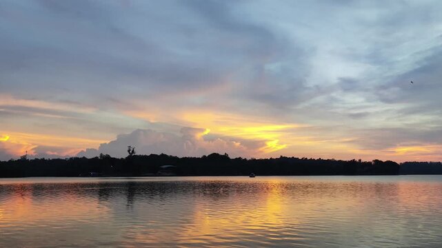 Landscape video footage of a lake on a warm afternoon with a clear sunset sky with golden hour color vibes in the background