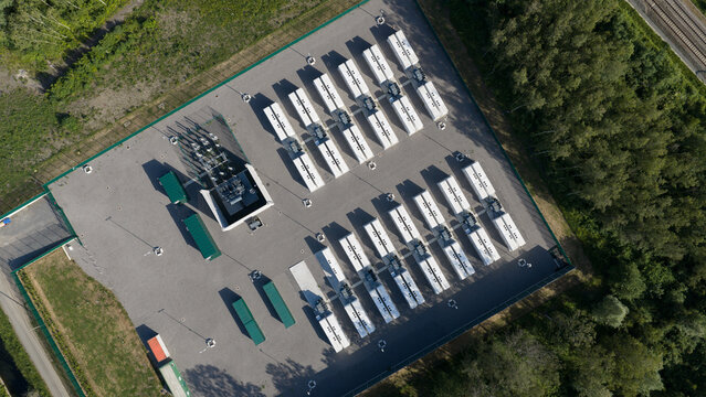 Aerial view of Elia TS Ville sur Haine battery storage facility with rows of white containers and green units surrounded by lush trees in Mons, Region wallonne, Belgium.