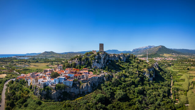 Aerial view of the medieval Castello della Fava and the historic village of Posada perched on a rocky hill under a clear blue sky Posada, Sardinia, Italy.