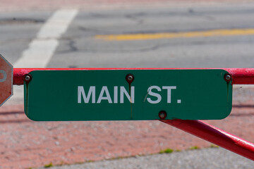 Main St sign visible on a barrier across a street with blurred background showing city features © George Sheldon