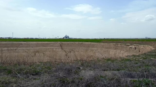 Ground-level footage showing a large sinkhole with steep eroded walls in a rural landscape. Geological formation, natural ground collapse, karst terrain, and dry soil textures are clearly visible.