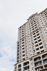 Fototapeta premium Elegant building with neutral colors. Sleek skyscraper under clear blue sky with soft hues. Contemporary tall structure characterized by uncluttered lines and muted tones