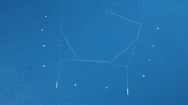 Aerial top down flight above traditional fixed fishing net patterns in blue waters off Ito Japan
