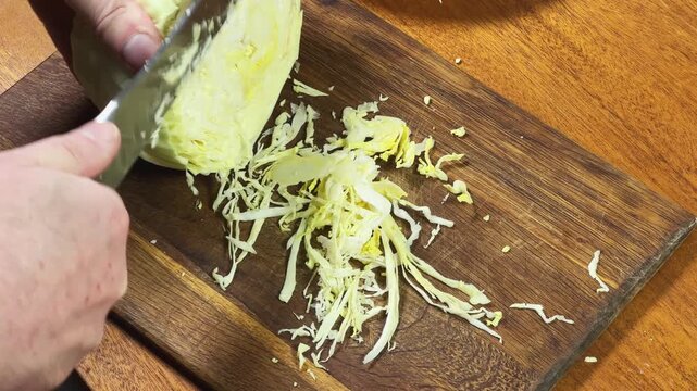 Shredding of white cabbage on cutting board for borscht cooking