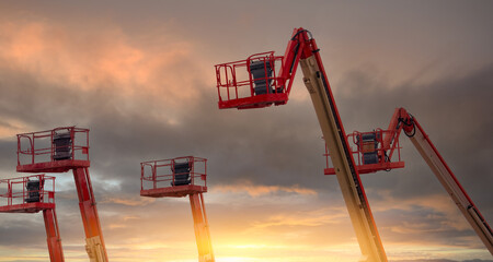 Articulated boom lift. Aerial platform lift. Telescopic boom lift with sunset sky. Mobile construction crane for rent. Repair hydraulic boom lift service. Crane dealership. Safety use of machinery. © Fahroni