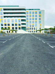 Fototapeta premium Empty parking lot in front of a modern building during a cloudy day with few trees lined along the sides