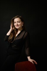 Fototapeta premium Captivating portrait of a woman in a stylish black outfit, exuding confidence and charm in a dimly lit setting