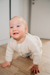 Fototapeta premium Happy Baby Crawling on Floor in Cozy Knitted Sweater