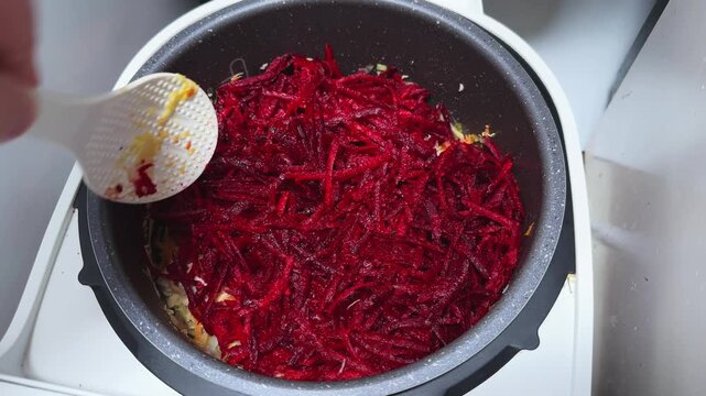 Stirring beet with other vegetables and pork in multi-cooker