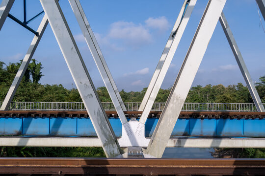 A close-up view of the structural steel framework and railway tracks of the historical Renville bridge in Kebumen, Central Java, Indonesia.