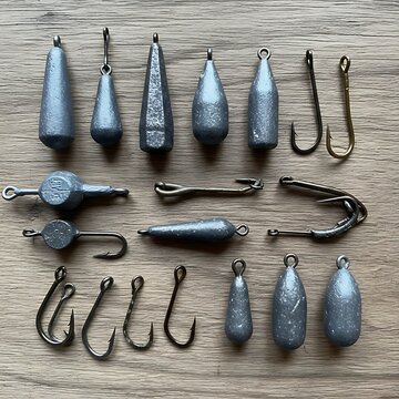Assorted Metal Fishing Weights and Hooks Arranged on Wooden Table