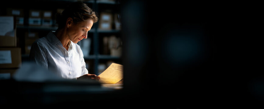 Woman reading document in dimly lit archive