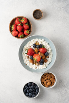 Fresh high protein cottage cheese berry bowl with blueberries, strawberries, chia seeds, granola and almonds served on light background with copy space