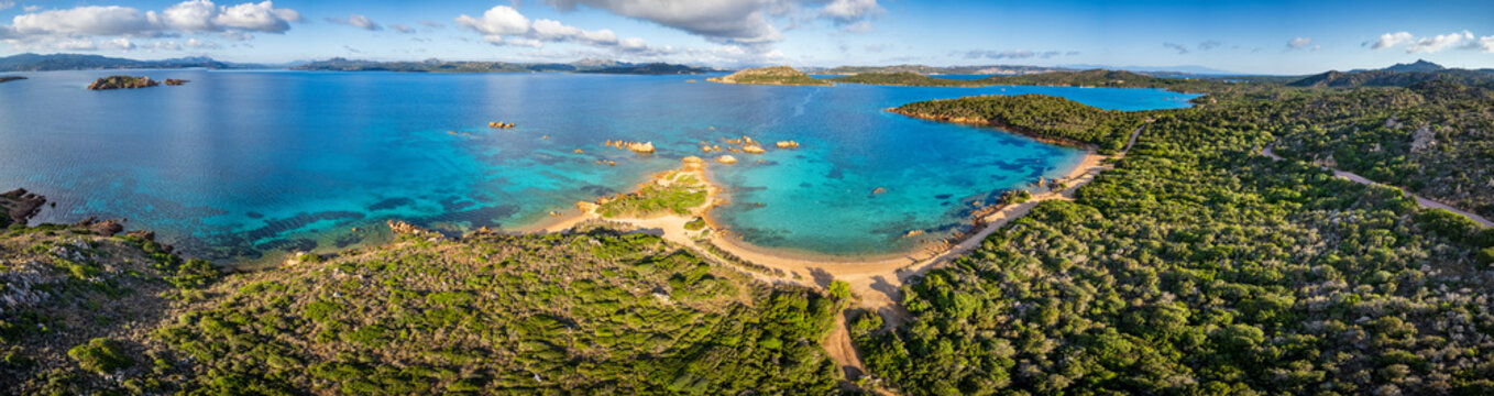 Aerial view of Spiaggia di Porto Palma with its turquoise waters, sandy shoreline, and lush green vegetation in La Maddalena, Sardegna, Italy.