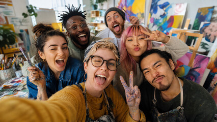 Obraz premium A vibrant group of artists joyfully capturing their creative moments in a colorful studio.