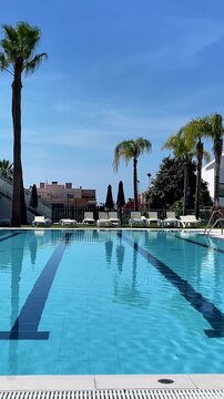 empty luxury swimming pool with palm trees under clear blue sky