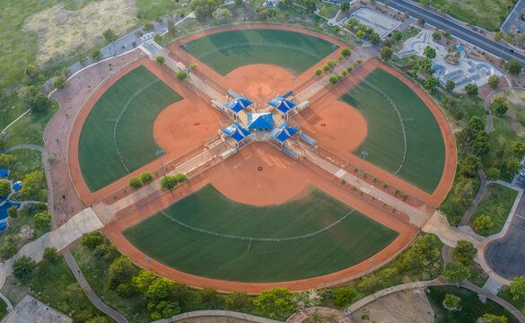 Aerial view of a baseball complex with four fields arranged in a circular pattern around a central hub with blue canopies in Summerlin South, Nevada, United States.