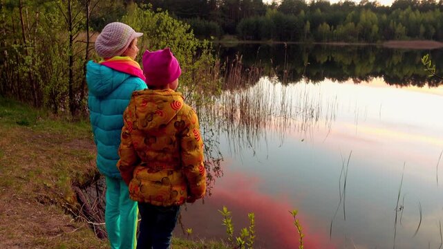 Two little sisters standing on lake shore