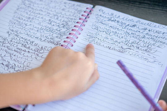 child hand writing made up cursive letters spiral notebook, pencil, imaginary alphabet practice, young student fills notebook, fake handwriting, learning write concept, school supplies Creative play