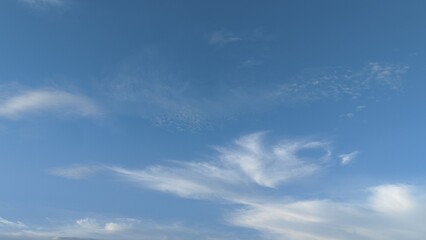 Fototapeta premium Clear blue sky with light white wispy clouds. natural background texture for sky replacement, background, wallpaper, presentation backdrop, graphic design with ample copy space.