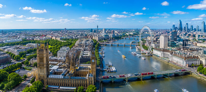 London cityscape showcases the historic Parliament buildings and the iconic river Thames winding through the dense urban center under a vibrant blue sky during a bright summer afternoon.