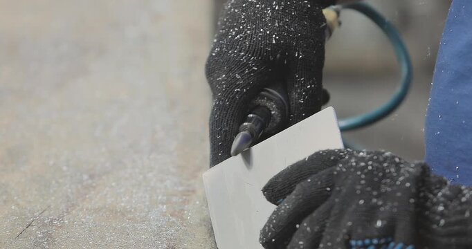 Worker operates a grinder. Grinding and processing of an aluminum part, first-person view. A worker processes an aluminum plate with a hand grinder. Carbide bur provides increased metal removal rates