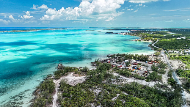Aerial view of George Town Cove with turquoise waters, lush coastal vegetation, and a small industrial area George Town, Exuma, The Bahamas.