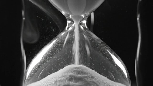 Black and white close up of an hourglass with smoke effects illustrating the passage of time