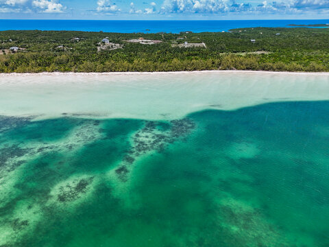 Aerial view of Turtle Beach featuring turquoise waters, coral reefs, and a white sand shoreline bordered by lush tropical vegetation in Central Eleuthera, The Bahamas.