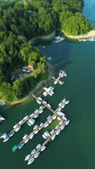 Vertical aerial view of luxury white yachts moored at a wooden pier in turquoise water © Mateusz