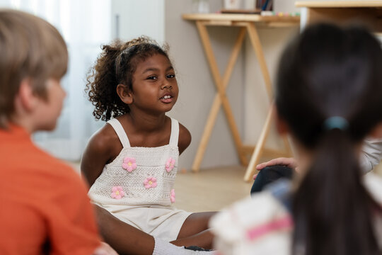 Young girl talks with multicultural classmate during classroom circle discussion, building communication skill, confidence, friendship, listening routine, and positive back to school engagement