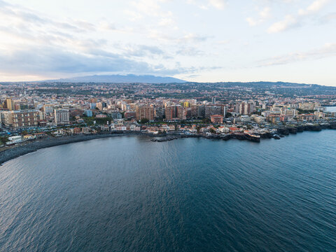 Aerial view of the coastal city of Catania with the urban skyline and Mount Etna in the background under a soft sky Catania, Sicily, Italy.