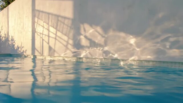 Close-up of water ripples in pool creating light reflections on wall