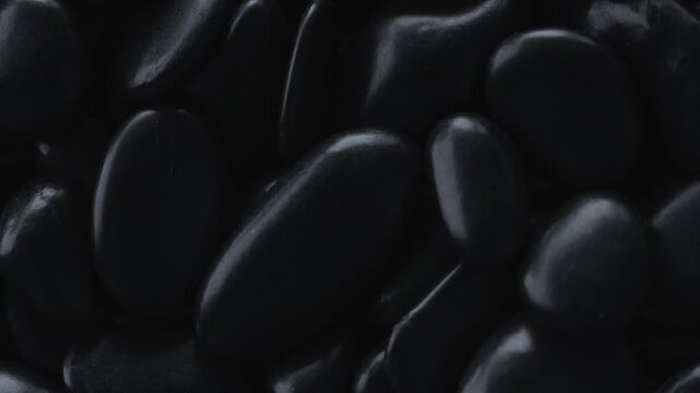 Close-up of polished black stones creating abstract natural texture, luxury wellness and meditation concept. 4K.