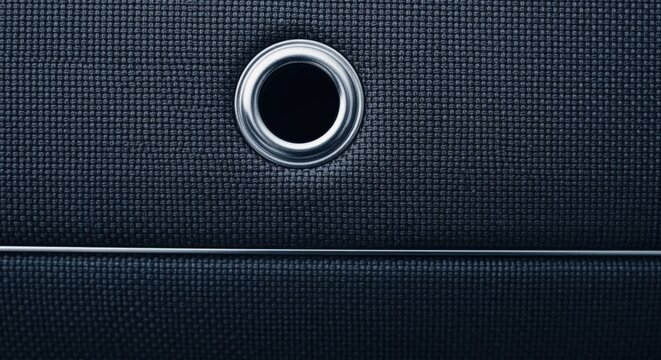 Close-up macro shot of dark textured fabric with metallic grommet detail and clean horizontal line