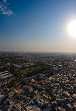 Aerial view of the Govt. Central Library and dense urban housing with green parks under a bright sun in Bahawalpur, Punjab, Pakistan.