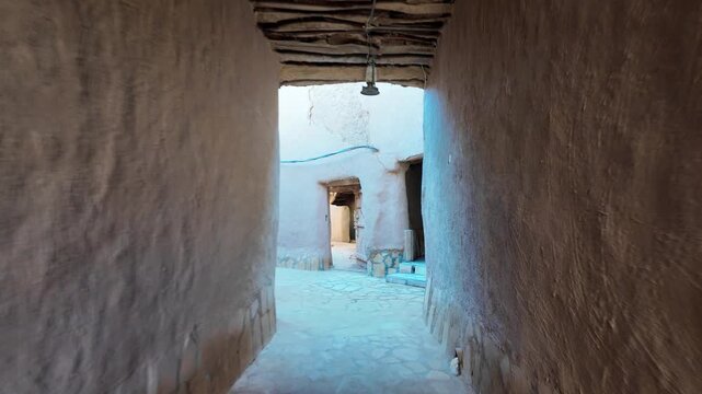 Ushaiqer Heritage Village entrance with a weathered wooden door and traditional lock opening to a courtyard of mud-brick walls, and a distinctive support pillar in Najdi style of Saudi Arabia