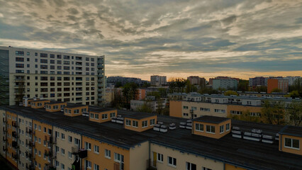 High angle view of a residential concrete block of flats with modern city skyscrapers in the background at sunset © Mateusz