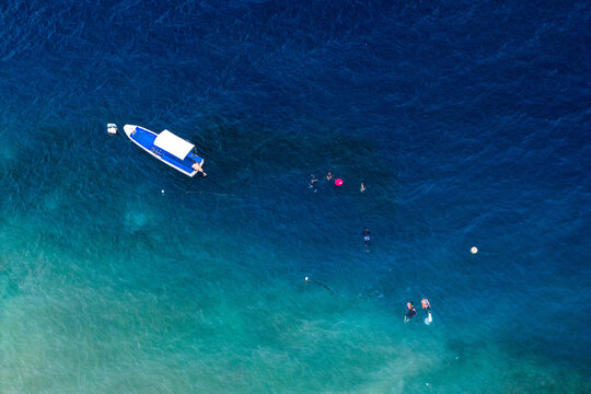 Aerial view of a boat and people snorkeling in the clear turquoise waters of the coral reef at Basdiot in Moalboal, Central Visayas, Philippines.