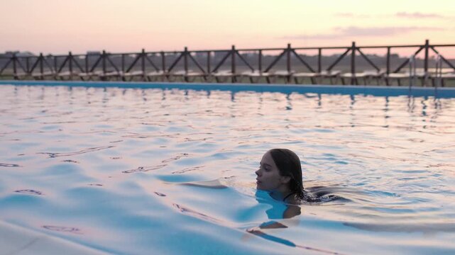 Girl in leopard swimsuit playing in the pool under the summer sun