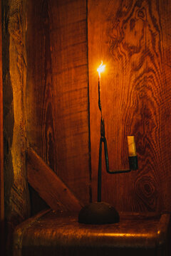 A pioneer-era reed lamp made with longleaf pine wood alongside a bed in a wood cabin in North Carolina