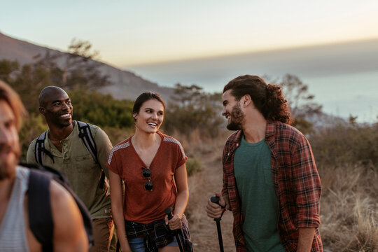Friends hiking on a coastal trail at sunset