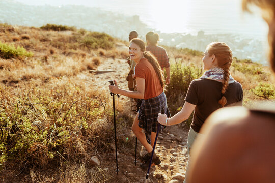Friends hiking on coastal mountain trail at sunset