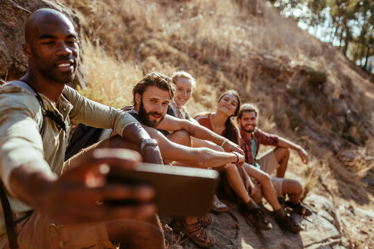 Friends taking selfie while resting on sunny hiking trail